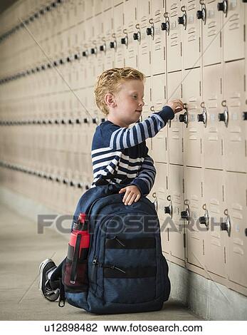 Stock Image - Boy with backpack by school lockers. Fotosearch