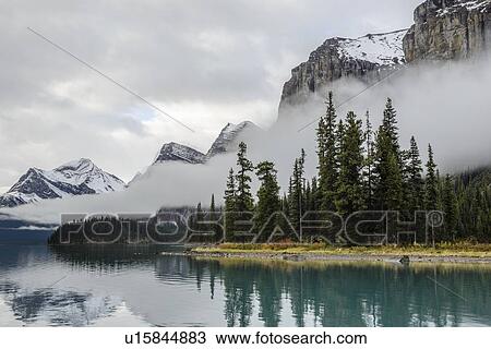 Stock Image - Canada, Alberta, Jasper, Mountains reflecting in Maligne Lake. Fotosearch