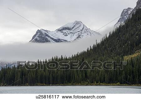 Stock Photo - Canada, Alberta, Jasper, Mountains reflecting in Maligne Lake. Fotosearch