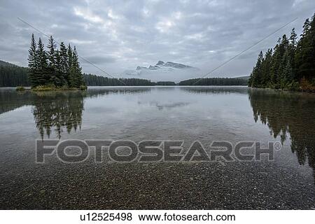 Stock Photo - Canada, Alberta, Two Jack Lake, Mountain peak in clouds. Fotosearch