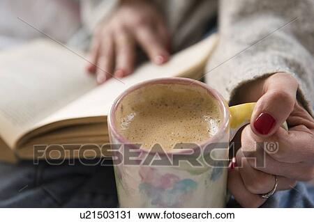 Stock Image - Close up of woman with coffee and book. Fotosearch