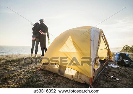 Stock Image - Couple by tent at beach. Fotosearch