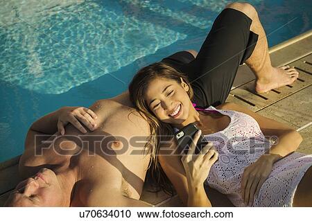 Stock Image - Couple relaxing by swimming pool. Fotosearch