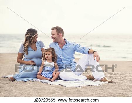 Stock Photography - Family sitting on blanket on beach. Fotosearch