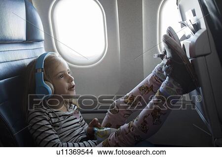 Girl wearing headphones on airplane View Large Photo Image Picture - Girl wearing headphones on airplane. Fotosearch