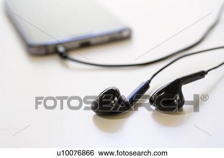 Stock Photograph - In-ear headphones with smartphone. Fotosearch