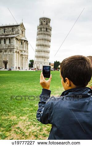 Stock Photo - Italy, Tuscany, Pisa, Rear view of teenage boy (16-17) photographing Leaning Tower of Pisa with smartphone. Fotosearch