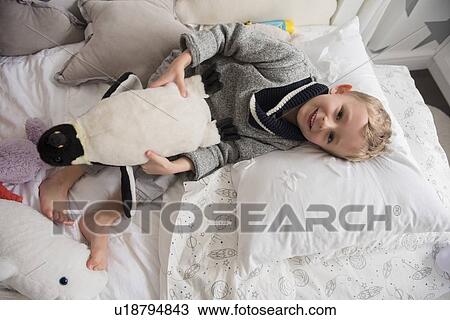Little boy (4-5) lying in bed with toy in hands View Large Photo Image Stock Image - Little boy (4-5) lying in bed with toy in hands. Fotosearch