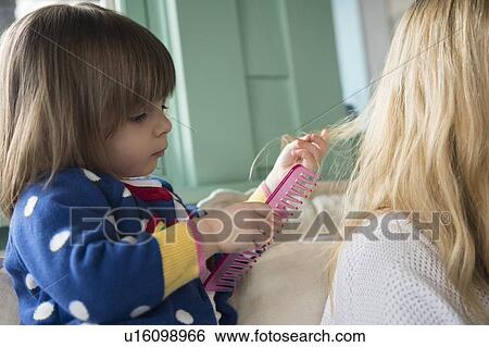 Stock Photograph - Little girl (2-3) combing mother's hair. Fotosearch
