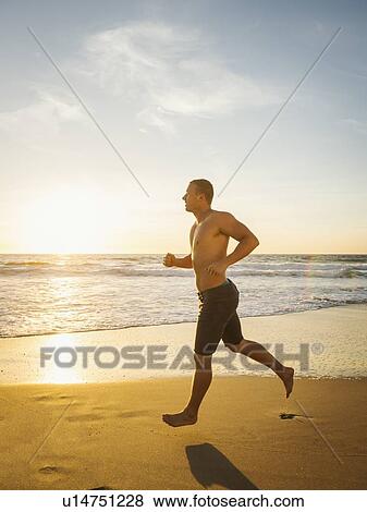 Stock Photo - Man jogging along beach. Fotosearch
