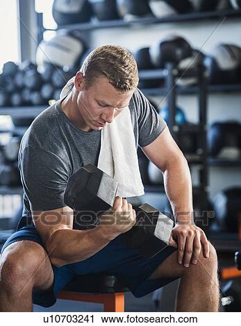 Stock Image - Mid adult man weight lifting. Fotosearch