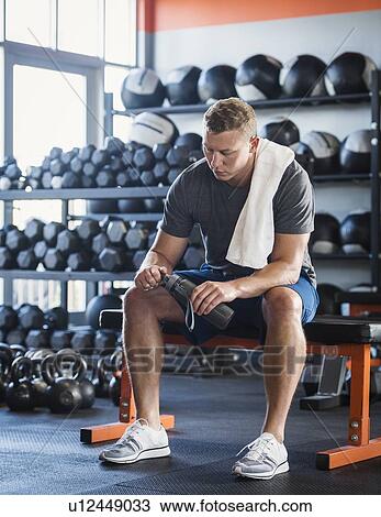 Mid adult man with towel and bottle in gym View Large Photo Image Stock Image - Mid adult man with towel and bottle in gym. Fotosearch
