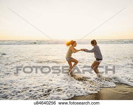 Mother and daughter jumping in waves View Large Photo Image Stock Photograph - Mother and daughter jumping in waves. Fotosearch