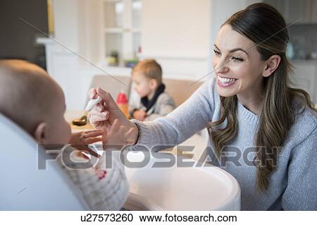 Stock Image - Mother feeding baby (18-23 months). Fotosearch