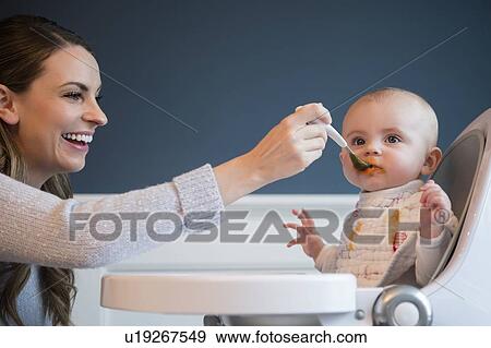 Stock Photo - Mother feeding baby (18-23 months). Fotosearch