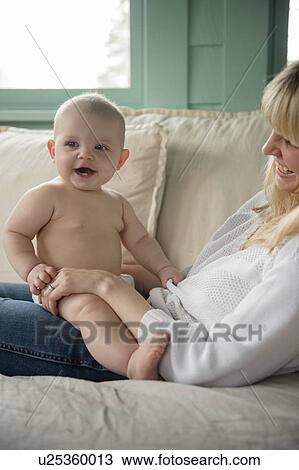 Stock Image - Mother sitting with baby (12-17 months) on couch. Fotosearch