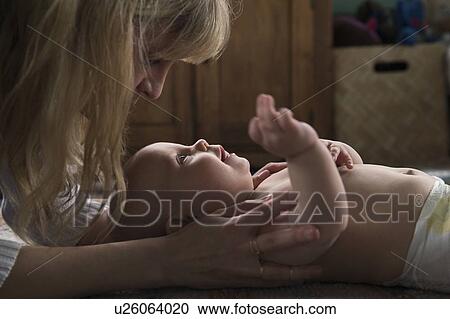 Stock Image - Mother with baby girl (12-17 months) at home. Fotosearch
