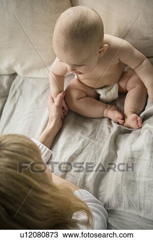 Stock Image - Mother with baby girl (12-17 months) in bed. Fotosearch