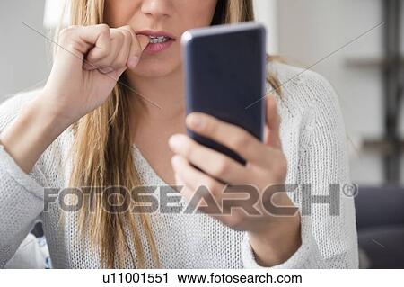 Stock Image - Nervous young woman using smart phone. Fotosearch