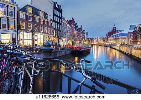 Stock Photograph - Netherlands, Amsterdam, Bicycles on bridge with canal in background. Fotosearch