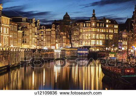 Stock Photograph - Netherlands, Amsterdam, Illuminated old town upon canal in Amsterdam. Fotosearch