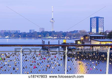 Stock Image - Netherlands, Rotterdam, Padlocks on railing with river in background. Fotosearch