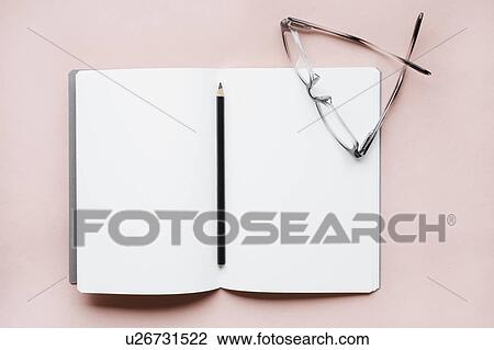 Stock Image - Pencil and glasses on open notebook. Fotosearch