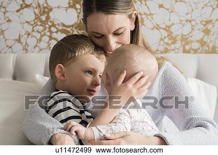 Stock Photo - Portrait of happy mother with two children (18-23 months, 4-5). Fotosearch