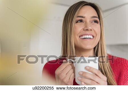 Stock Photography - Portrait of smiling young woman holding mug. Fotosearch