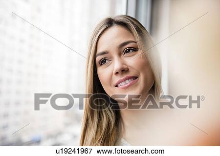 Portrait of young woman looking through window View Large Photo Image Stock Photo - Portrait of young woman looking through window. Fotosearch