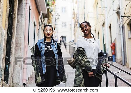 Stock Photography - Portugal, Lisbon, Two smiling young women walking outdoors. Fotosearch