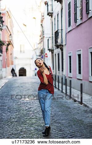 Stock Photograph - Portugal, Lisbon, Young woman blowing kiss in old town. Fotosearch