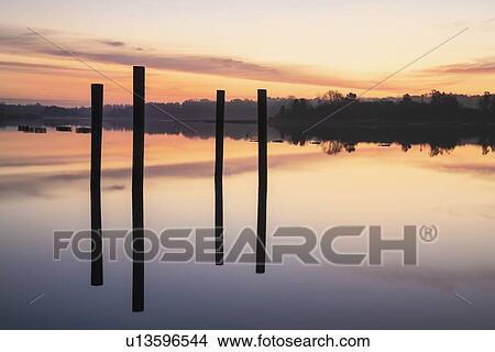 Picture - Posts in sea at sunrise. Fotosearch