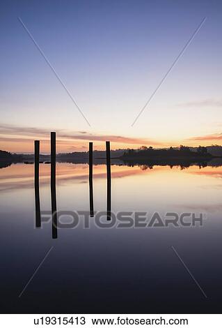 Stock Image - Posts in sea at sunrise. Fotosearch