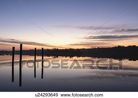 Stock Photo - Posts in sea at sunrise. Fotosearch