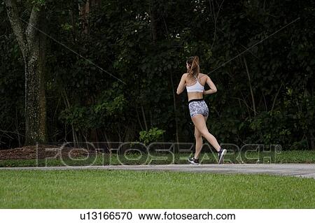 Rear view of woman jogging in park View Large Photo Image Stock Image - Rear view of woman jogging in park. Fotosearch