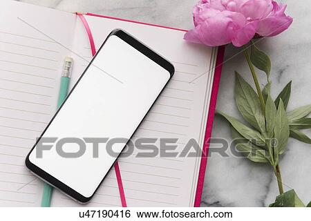Stock Photograph - Smart phone and flower on note pad. Fotosearch