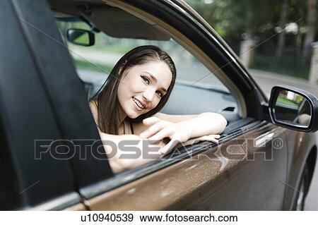 Smiling young woman sitting in car View Large Photo Image Stock Photo - Smiling young woman sitting in car. Fotosearch
