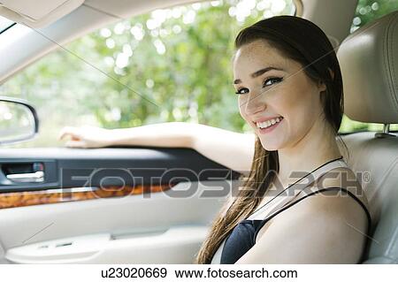 Smiling young woman sitting in car View Large Photo Image Stock Photo - Smiling young woman sitting in car. Fotosearch