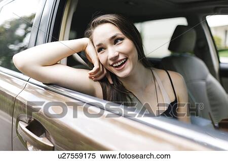 Stock Photography - Smiling young woman sitting in car. Fotosearch