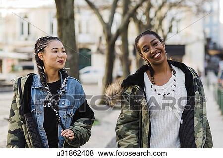 Two smiling young women walking outdoors View Large Photo Image Stock Photo - Two smiling young women walking outdoors. Fotosearch