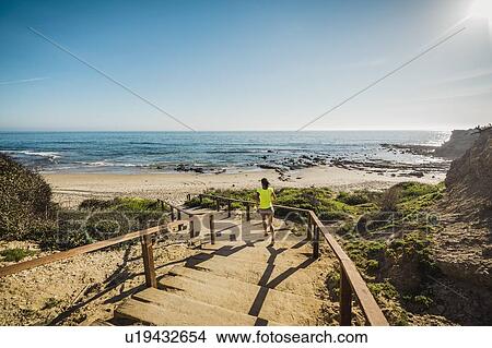 USA, California, Newport Beach, Woman running down stairs View Large Photo Image Picture - USA, California, Newport Beach, Woman running down stairs. Fotosearch