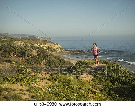 Stock Image - USA, California, Newport Beach, Woman running along cliff. Fotosearch