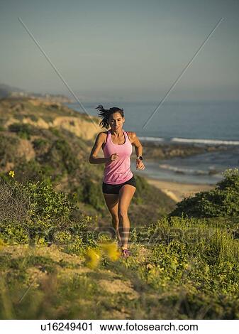 Stock Image - USA, California, Newport Beach, Woman running along cliff. Fotosearch