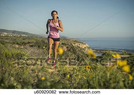 Stock Image - USA, California, Newport Beach, Woman running along cliff. Fotosearch