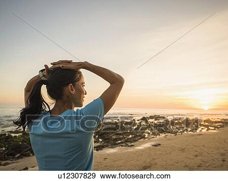 Stock Photo - USA, California, Newport Beach, Woman exercising on beach. Fotosearch