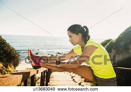 Stock Photo - USA, California, Newport Beach, Woman stretching on beach. Fotosearch
