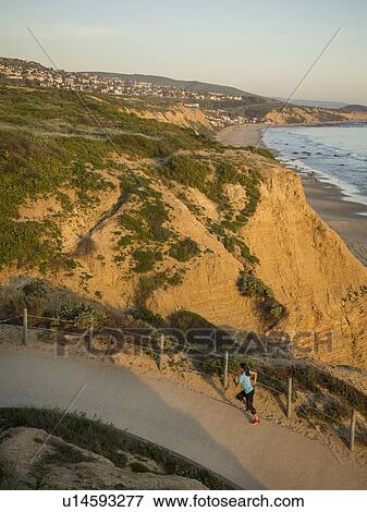 Stock Photo - USA, California, Newport Beach, Woman running along footpath. Fotosearch