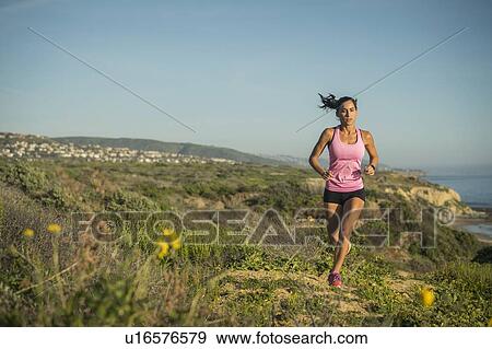 Stock Photo - USA, California, Newport Beach, Woman running along cliff. Fotosearch