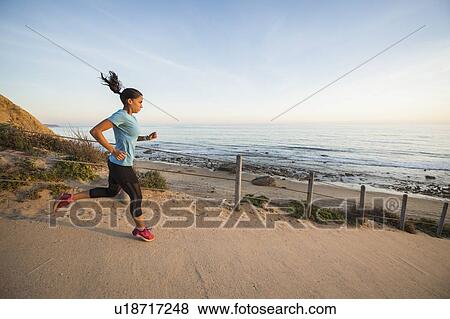 Stock Photo - USA, California, Newport Beach, Woman running along footpath. Fotosearch